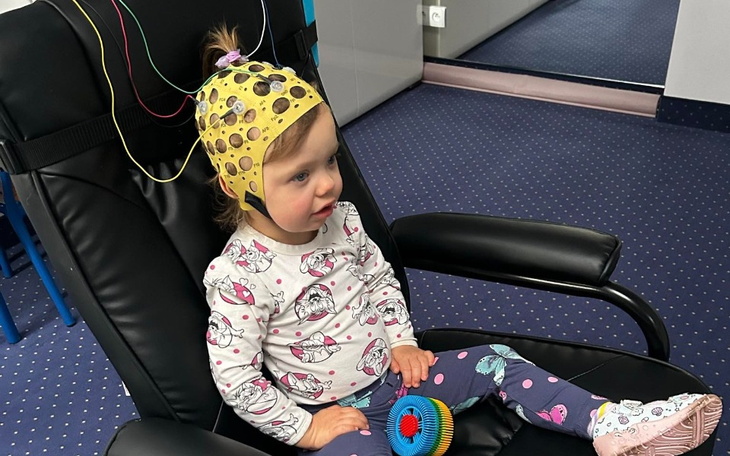 Mała dziewczynka w fotelu, z elektrodami na głowie.