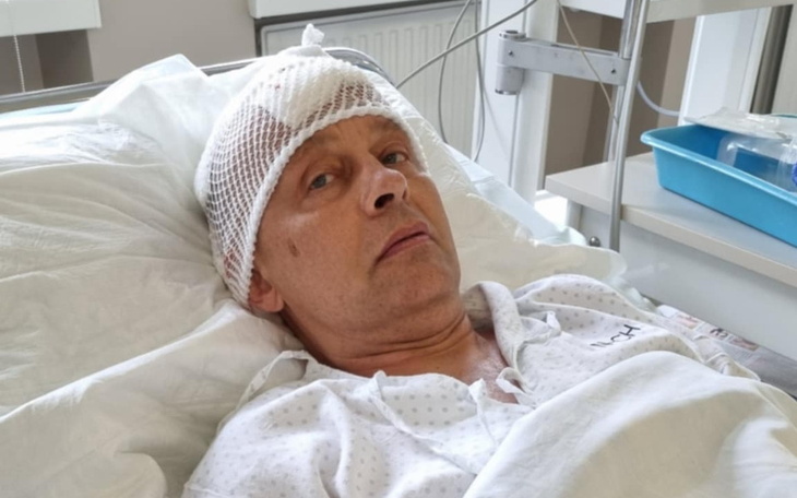 Mężczyzna w szpitalu z opatrunkiem na głowie.