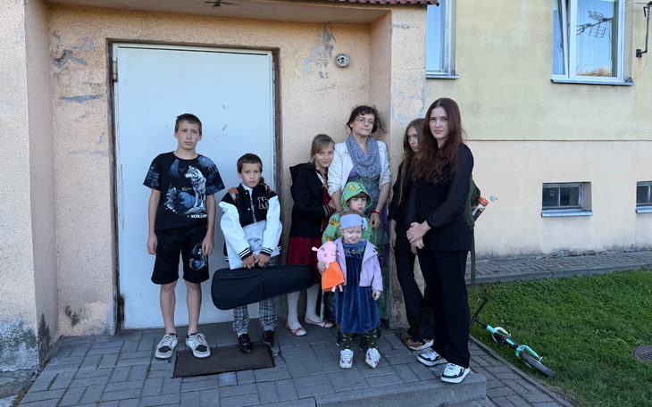 Grupa dzieci i dorosłych pozujących przed budynkiem.