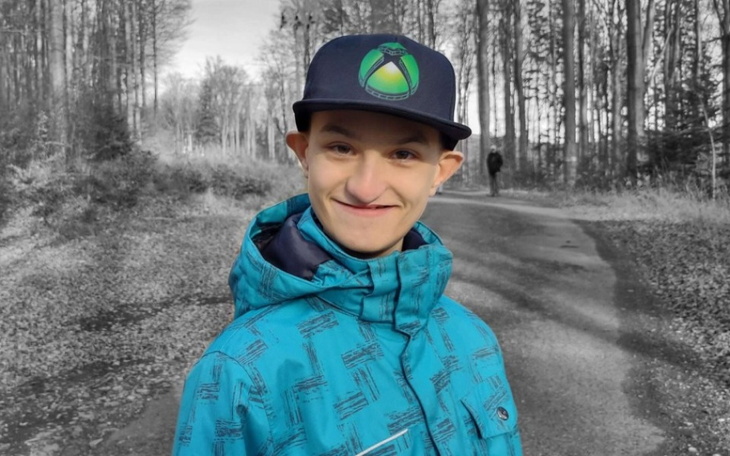 Młody mężczyzna w kolorowej kurtce na leśnej drodze.