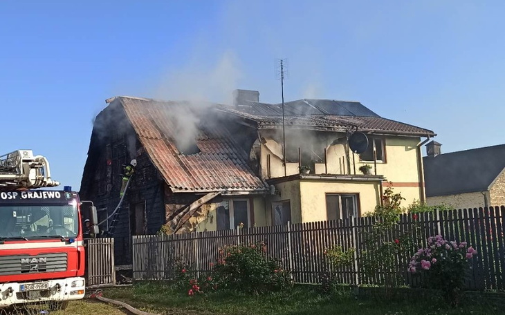 Dom w ogniu, z dymem wydobywającym się z dachu.