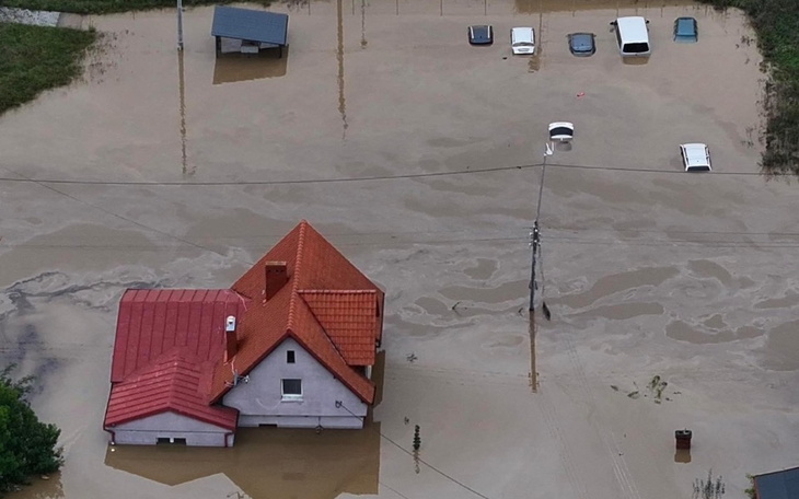 Widok z lotu ptaka na zalany dom i samochody.