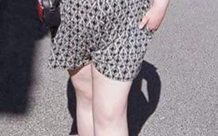 Osoba w szortach na tle ulicy, w letnim stylu.