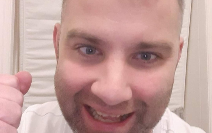 Mężczyzna z uśmiechem, pokazujący kciuk w górę.