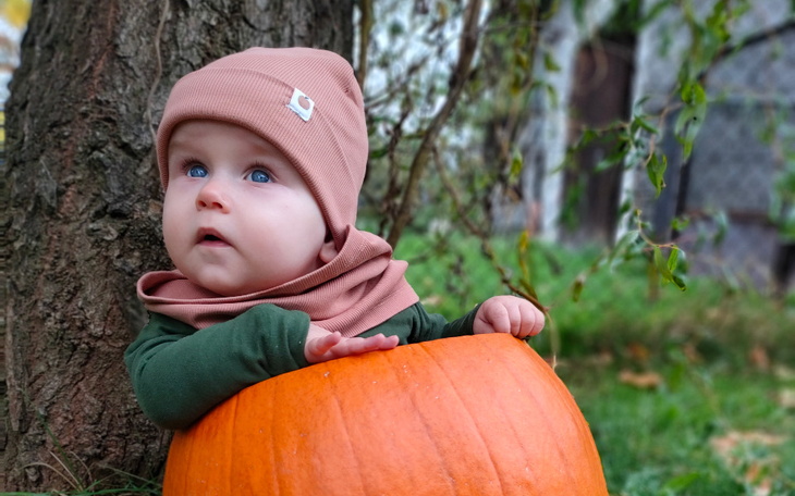 Małe dziecko w dyni, z zachwytem patrzące w górę.
