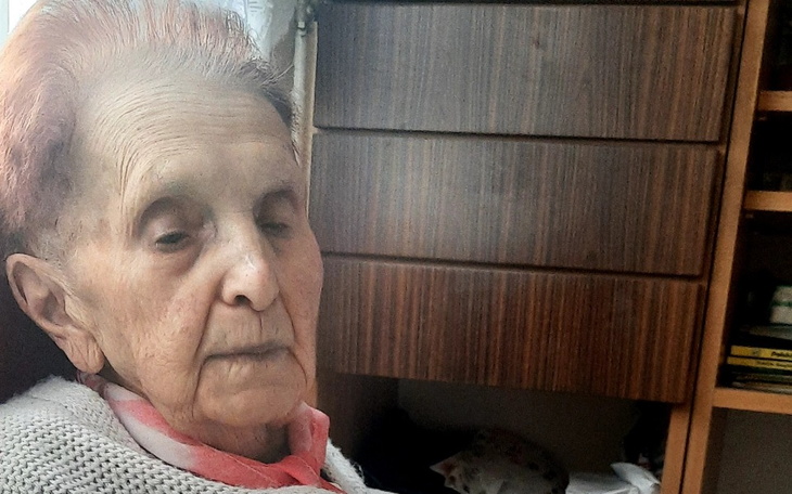 Starsza kobieta w spokojnej chwili, siedząca w fotelu.