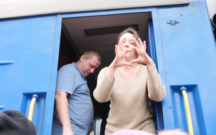 Kobieta gestykulująca w drzwiach pociągu.