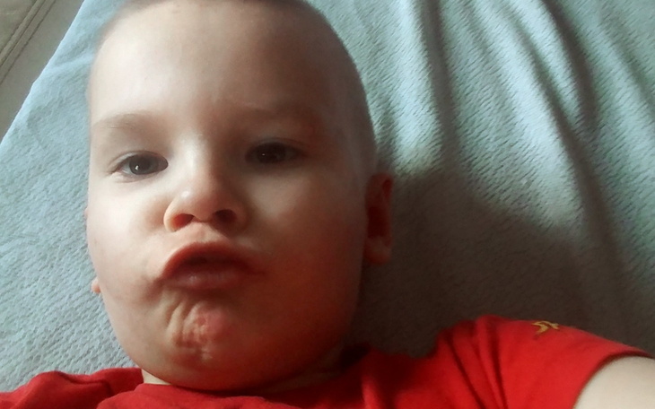 Mały chłopiec leżący na łóżku, robiący zabawne miny.