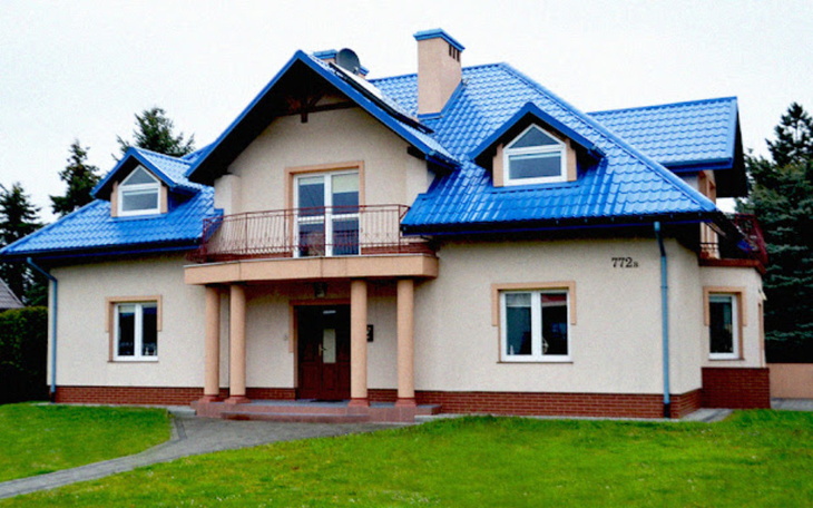 Nowoczesny dom z niebieskim dachem i dużym ogrodem.