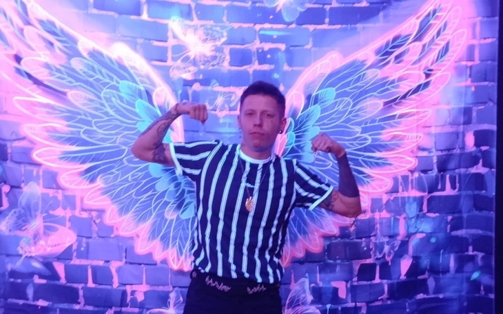 Mężczyzna w paskowanej koszulce, pozujący z rozpostartymi skrzydłami.