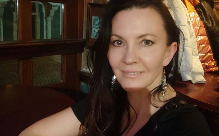 Portret kobiety w kawiarni, uśmiechającej się do kamery.