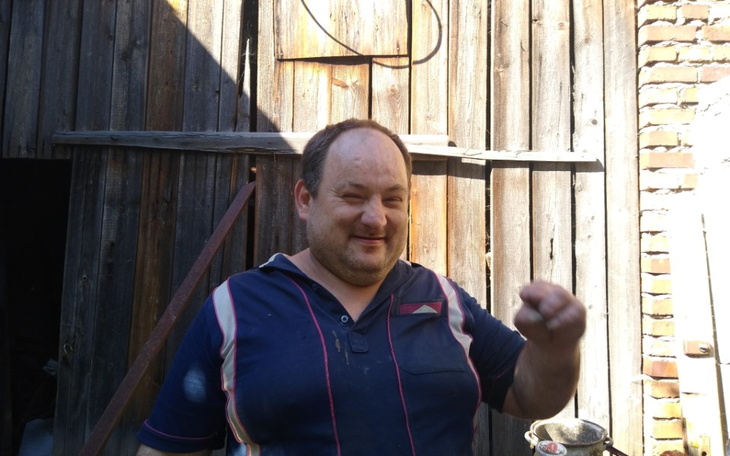 Mężczyzna uśmiechający się na tle drewnianej ściany.