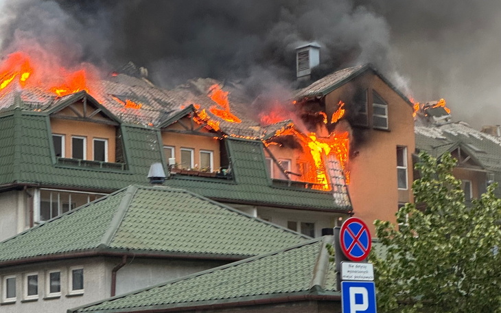 Pożar na dachu budynku, z płomieniami i dymem.