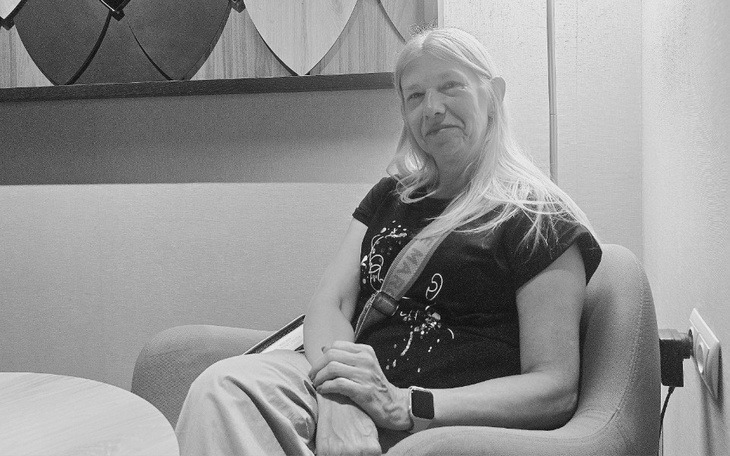 Kobieta z długimi włosami, uśmiechająca się w fotelu.