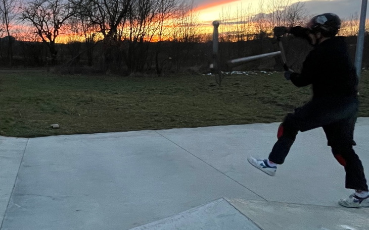 Osoba rzucająca przedmiot na tle zachodzącego słońca.