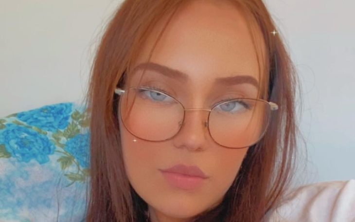 Młoda kobieta w okularach, pozująca do zdjęcia.