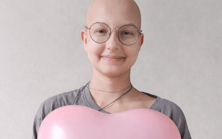 Dziecko uśmiecha się trzymając różowy balonik