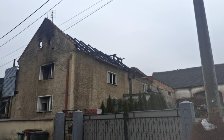 Zniszczony budynek z uszkodzonym dachem, widok z zewnątrz.