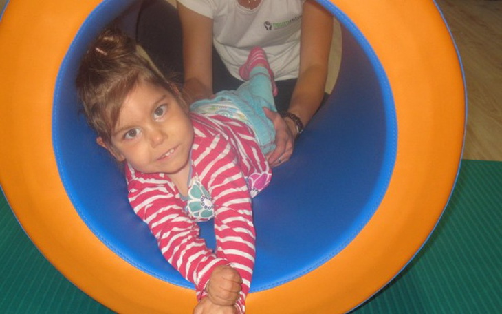 Dziewczynka bawiąca się w kolorowym tunelu.