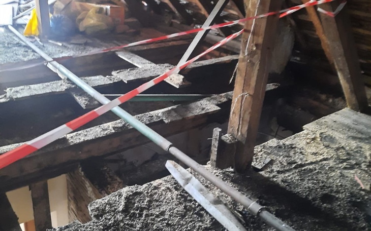 Zniszczony dach z widocznymi uszkodzeniami i materiałami budowlanymi.