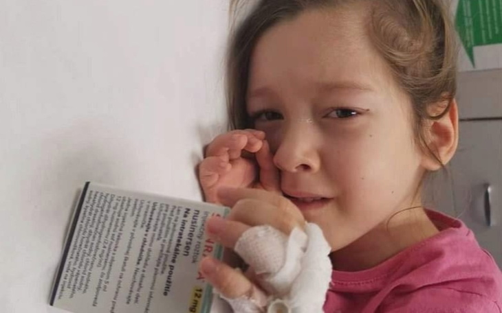 Zmartwiona dziewczynka w szpitalu z opatrunkiem na ręce.