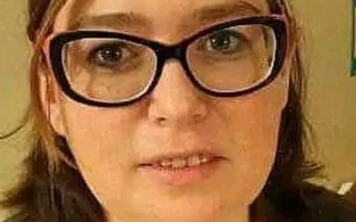 Kot patrzący w obiektyw na tle trawy.