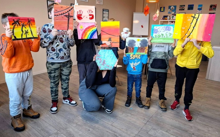 Grupa dzieci trzymających swoje prace plastyczne.