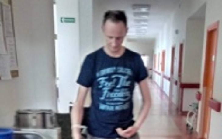 Mężczyzna w niebieskiej koszulce w korytarzu.