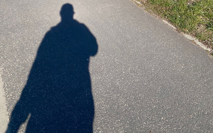 Cień osoby na drodze.