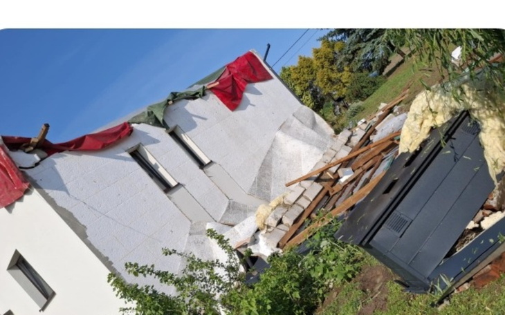 Zniszczony budynek z odsłoniętymi ścianami, w tle zieleń.