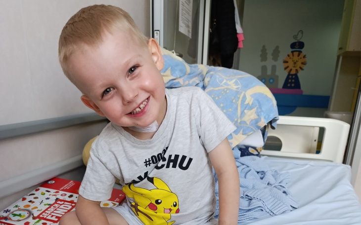 Uśmiechnięty chłopiec w szpitalnym łóżku, w koszulce z Pikachu.