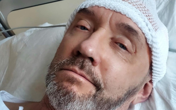 Mężczyzna w szpitalu, z opatrunkiem na głowie.