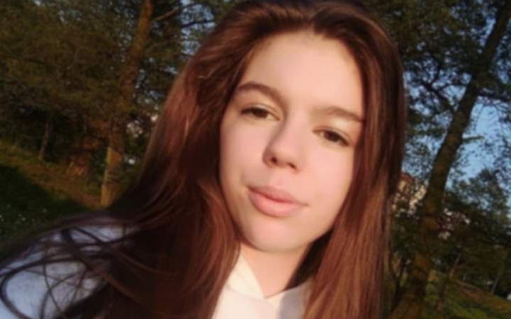 Młoda dziewczyna na tle natury, uśmiechnięta i radosna.