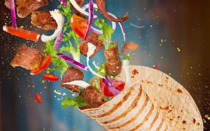 Tortilla z mięsem i świeżymi warzywami w powietrzu.