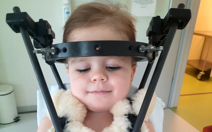 Małe dziecko w specjalnym urządzeniu medycznym, z uśmiechem na twarzy.