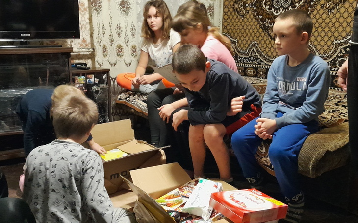 Dzieci zbierające się wokół pudełka z prezentami, pełne radości.