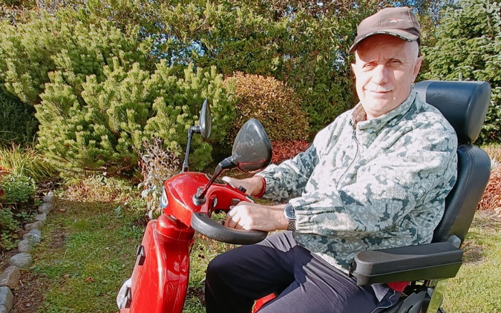 Starszy mężczyzna na skuterze elektrycznym w ogrodzie.