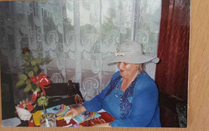 Kobieta w kapeluszu przy stole, otoczona dekoracjami i kwiatami.