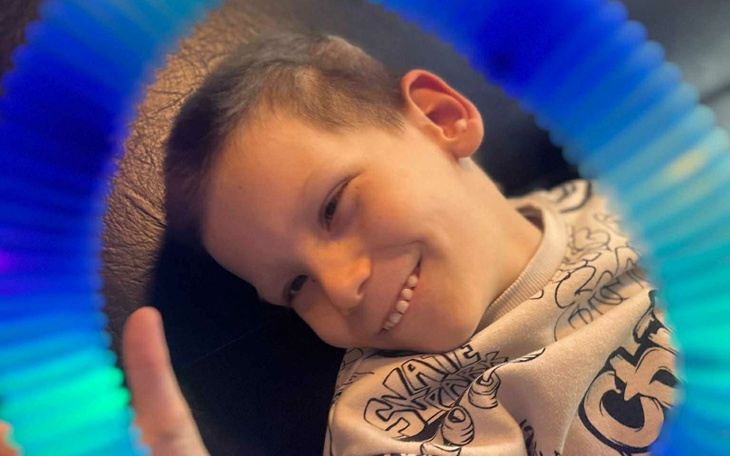 Chłopiec uśmiecha się, trzymając kolorowy pierścień.