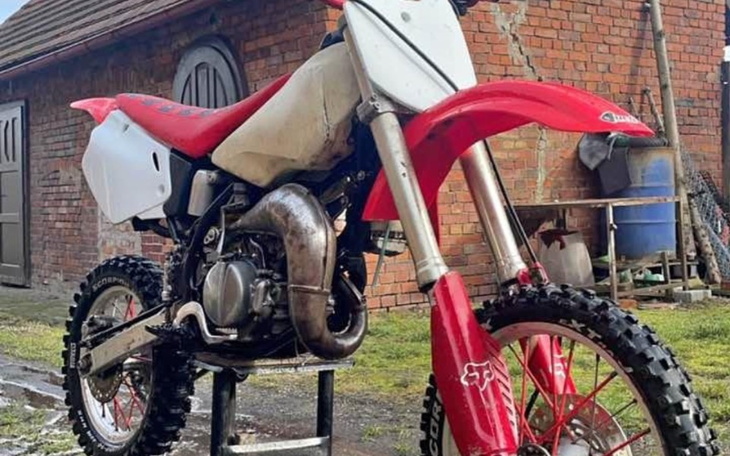 Czerwony motocykl terenowy na stojaku.