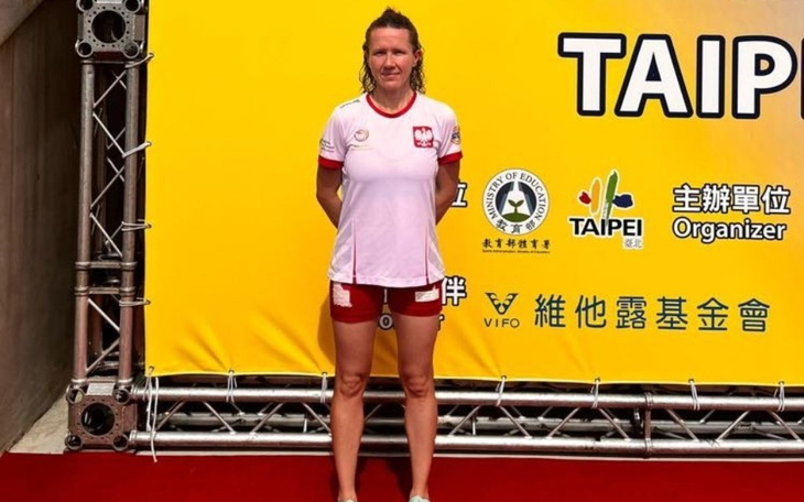 Kobieta w stroju sportowym, pozująca na tle banera z napisem Taipei.