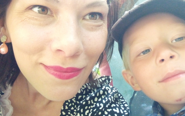 Portret matki z dzieckiem, uchwycony w uśmiechu.