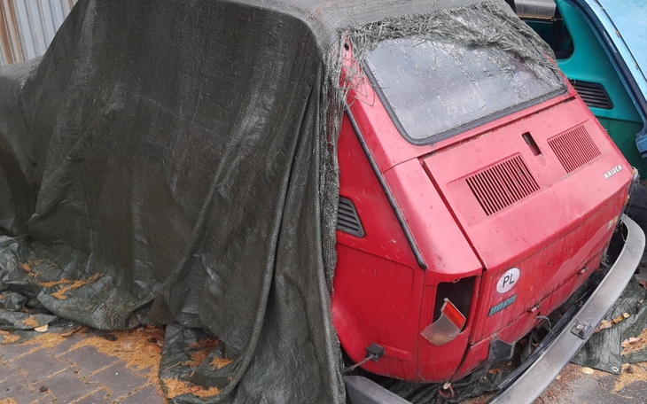 Zasłonięty stary samochód, pokryty plandeką.