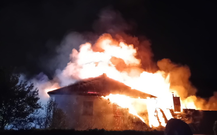 Dziecko w kapturku patrzy na wejście do drzwi z okrągłym oknem w tle.