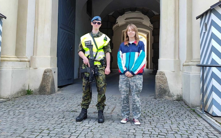 Funkcjonariusz policji i młody mężczyzna pozujący przed bramą.