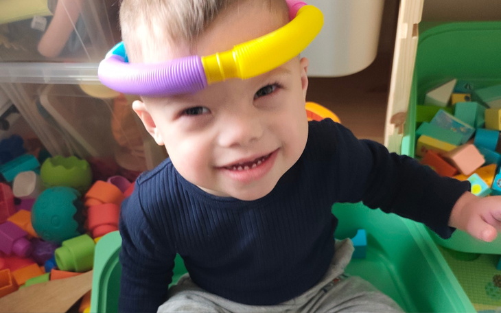 Uśmiechnięty chłopiec bawiący się kolorowymi klockami.