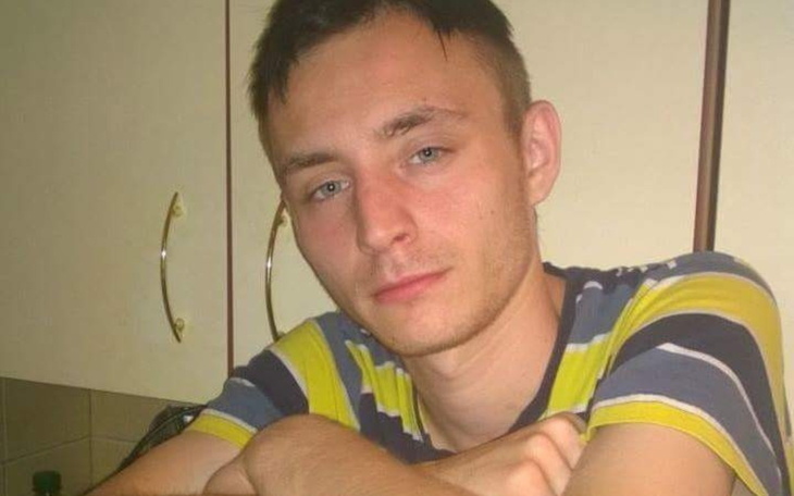 Młody mężczyzna siedzi przy stole, z zamyśloną miną.