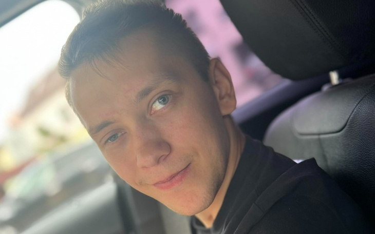 Młody mężczyzna uśmiechający się w samochodzie.