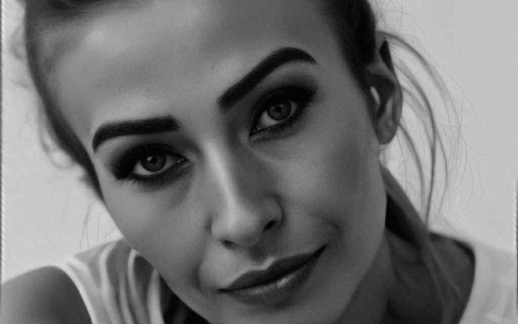 Portret kobiety z wyrazistym makijażem i uśmiechem.