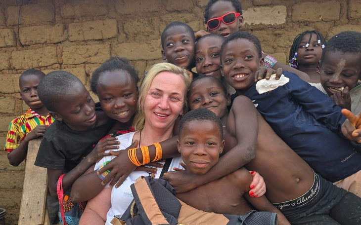 Grupa dzieci z uśmiechami, pozująca z dorosłą osobą.